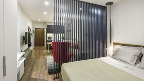 A hotel room with a bed, a desk, a chair, and a partition. - Olvios Design Suite (Thessaloniki)