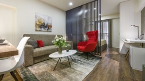 A modern living room with a grey sofa, a red armchair, a white coffee table, and a painting on the wall. - Olvios Design Suite (Thessaloniki)