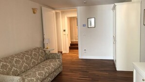 A living room with a patterned sofa, a white cabinet, and a wooden floor. - Suites alla Maddalena (Venice)