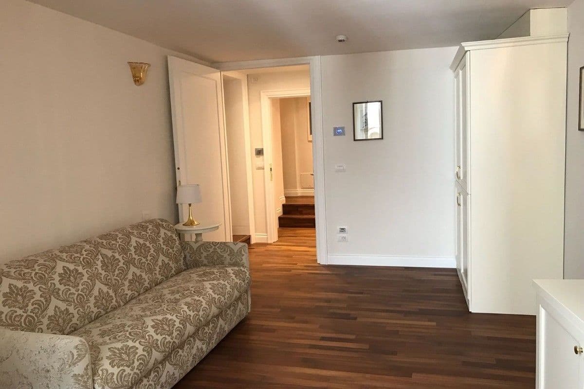 A living room with a patterned sofa, a white cabinet, and a wooden floor.