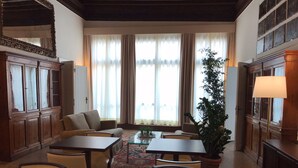 A traditional room with a sofa, two tables, chairs, a potted plant, and a lamp. - Suites alla Maddalena (Venice)