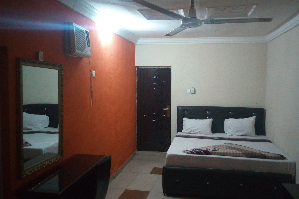 A bedroom with a bed, a dresser, a mirror, and a ceiling fan.
