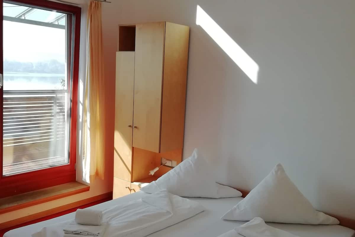 A hotel room with a bed, a wardrobe, and a window with curtains.