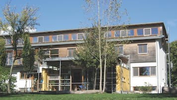 Un edificio moderno de varios pisos con techo plano, ventanas grandes y un área de entrada cubierta.