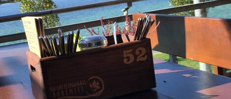 A wooden box with the number 52 on it, placed on a wooden table with a view of a lake and trees in the background.