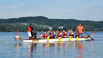Ein Drachenboot mit mehreren Ruderern, ein Steuermann vorne und eine Frau hinten.