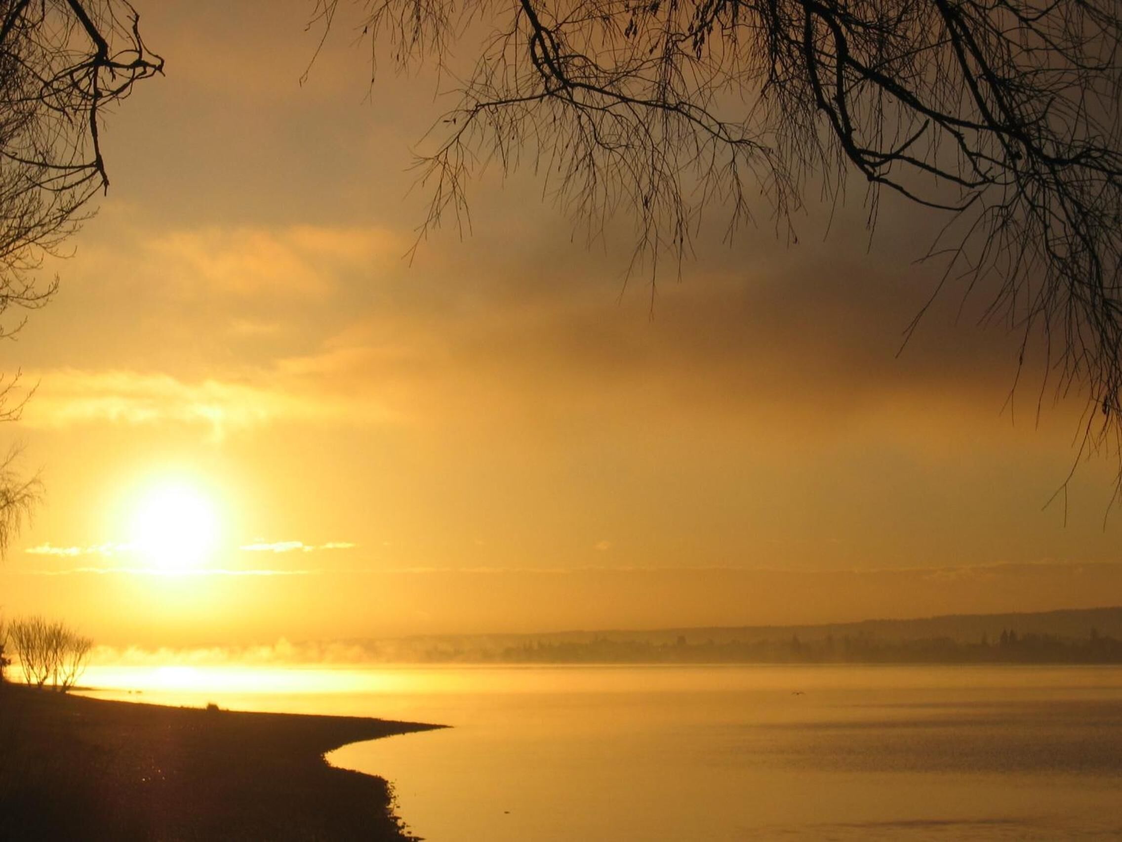 Ein friedlicher See bei Sonnenuntergang mit klarem Himmel und ruhiger Wasserfläche.