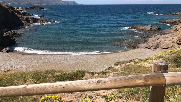 A coastal landscape with rocky terrain, a sandy beach, and a wooden fence. - Alberg Costa Brava - Hostel (Llanca)