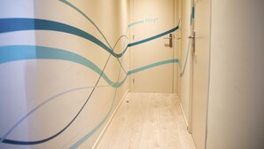 A hallway with a wooden floor and walls featuring abstract blue and teal designs. - Alberg Costa Brava - Hostel (Llanca)