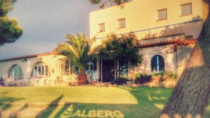 A two-story building with a tiled roof, arched windows, and a well-maintained lawn. - Alberg Costa Brava - Hostel (Llanca)