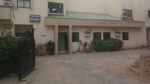 A guest house with a paved courtyard, a metal gate, and potted plants. - Progandy Guest House Annex (Abuja)