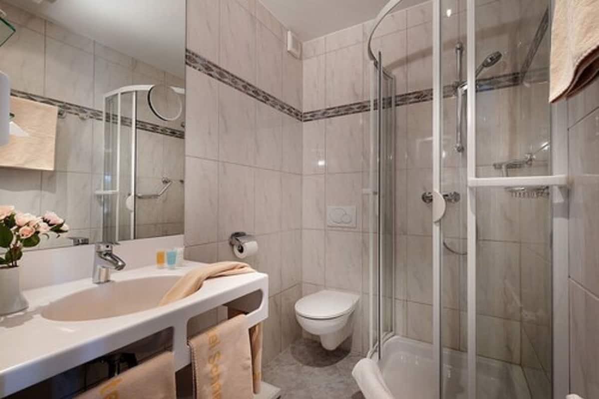 A modern bathroom with a glass-enclosed shower, a white sink, and a toilet.