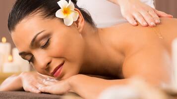 A person receiving a massage with candles in the background.