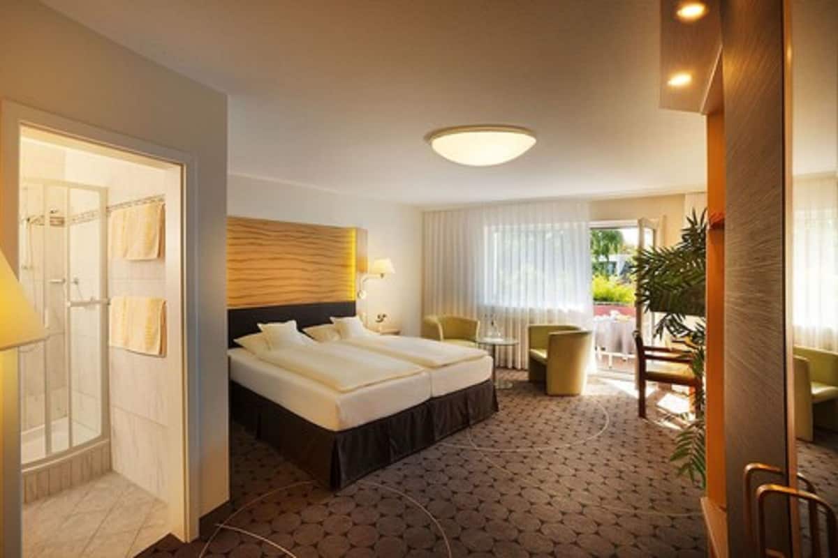 A hotel room with a large bed, a separate seating area, and a view of the outdoors.