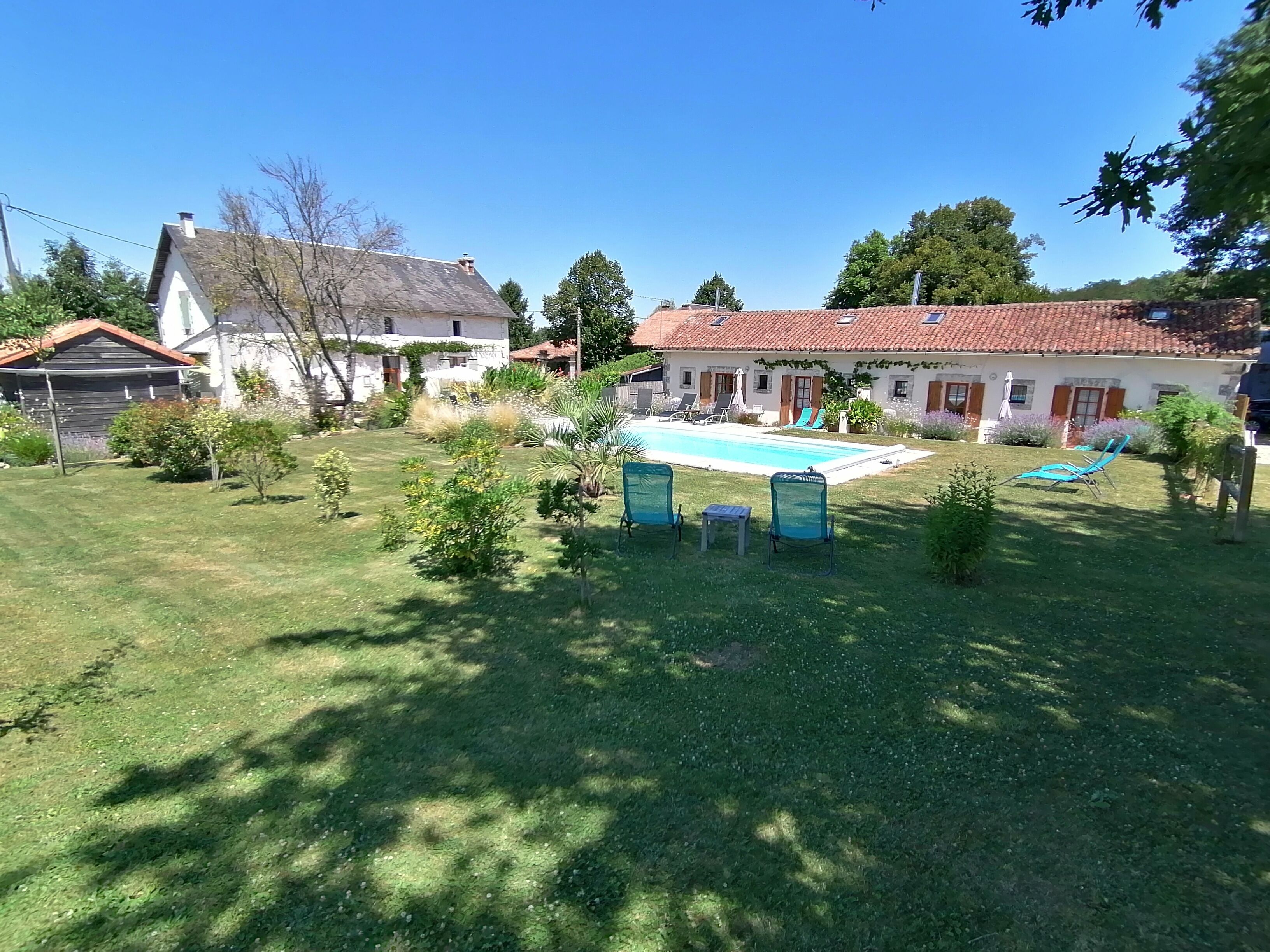 A residential property with a swimming pool, multiple lounge chairs, and a well-maintained lawn.