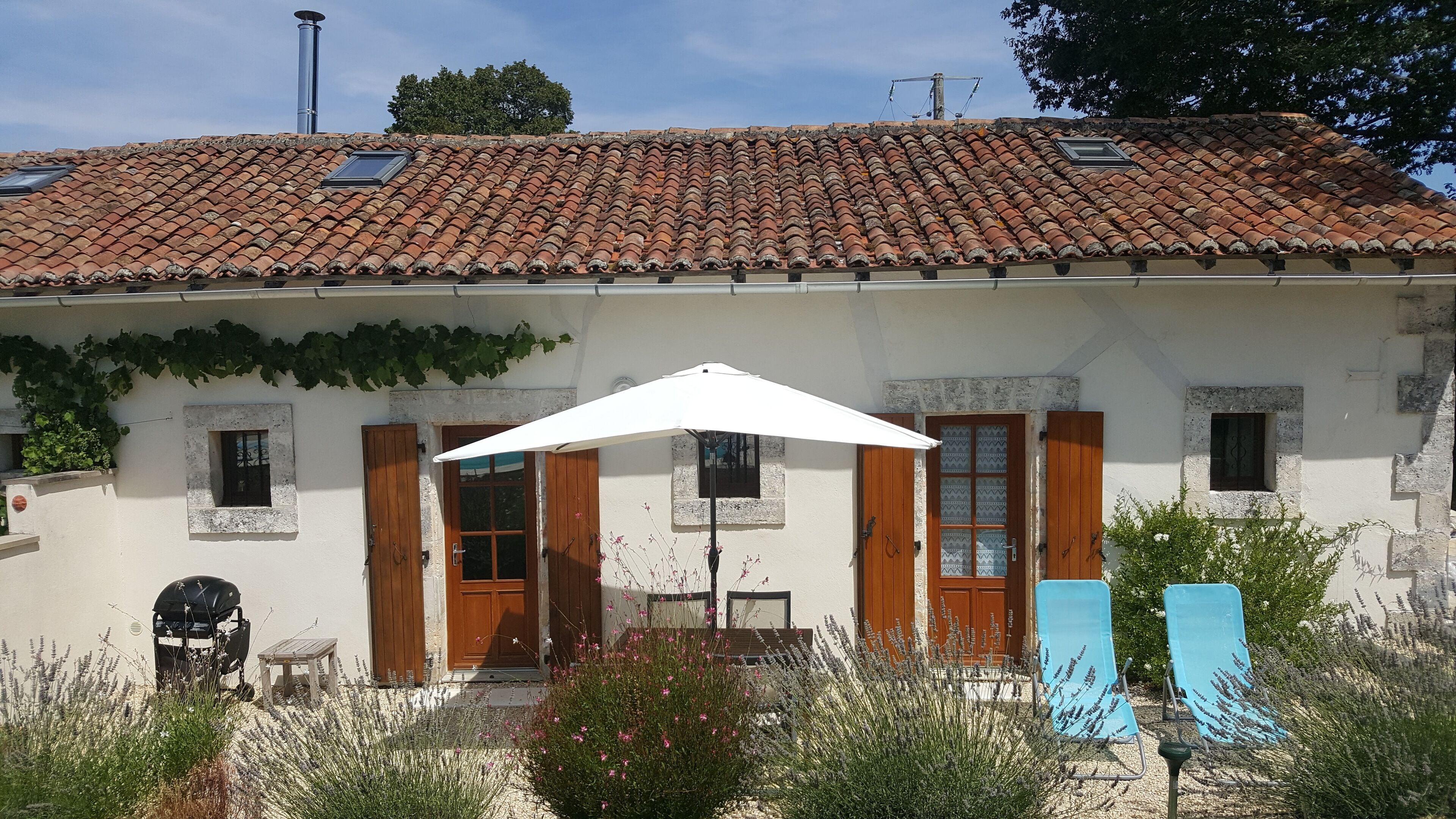 A building with a tiled roof, wooden shutters, and a white umbrella.