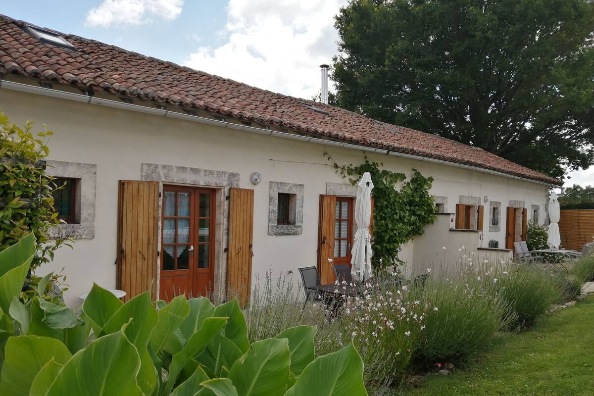 Un edificio de dos pisos con techo de tejas, puertas de madera y un ventanal pequeño.