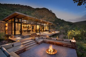 A modern outdoor living area with a fire pit, stone steps, and a dining area with outdoor seating.