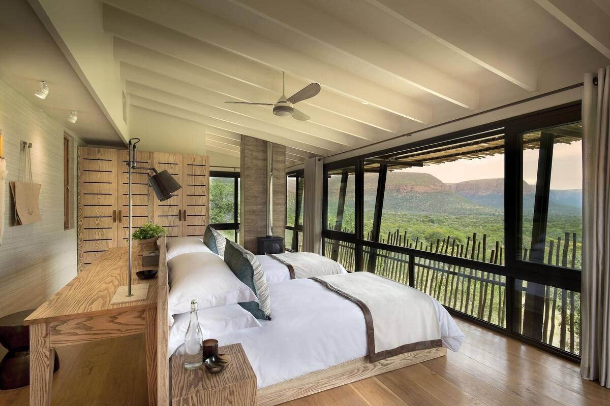 Ein Schlafzimmer mit einem großen Bett, einem Deckenventilator, einem Holzschrank und Blick auf eine Berglandschaft.