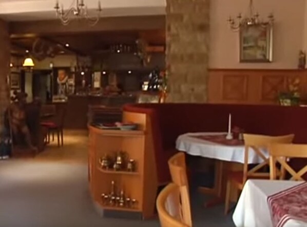 Un acogedor interior de restaurante con mobiliario de madera, una zona de bar y una pared de piedra.