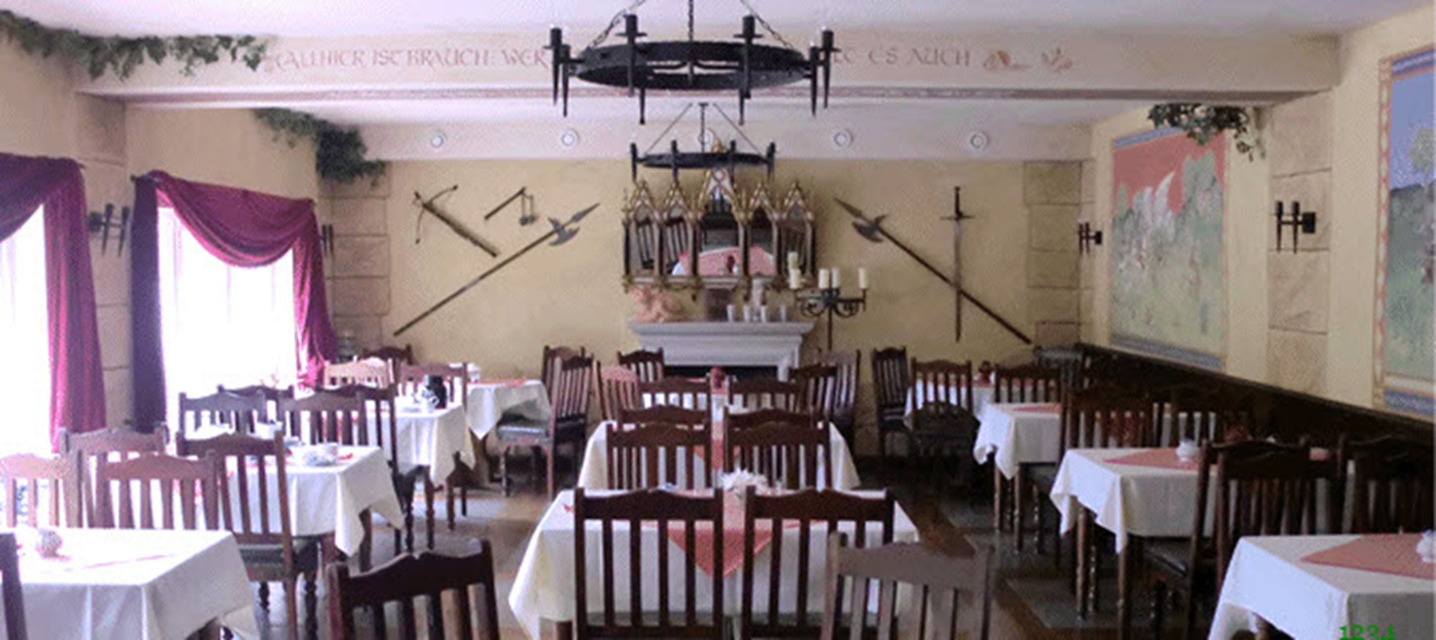 A dining area with tables and chairs, a chandelier, and a mural on the wall.