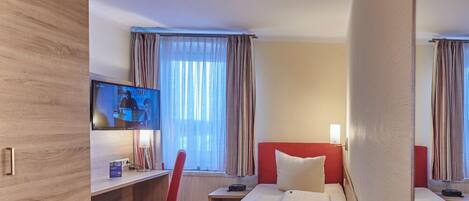Una habitación de hotel con dos camas, un escritorio, una silla y un televisor.