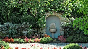 A garden with a stone wall, a fountain, and various flowering plants. - Villa Stefano (Dicomano)