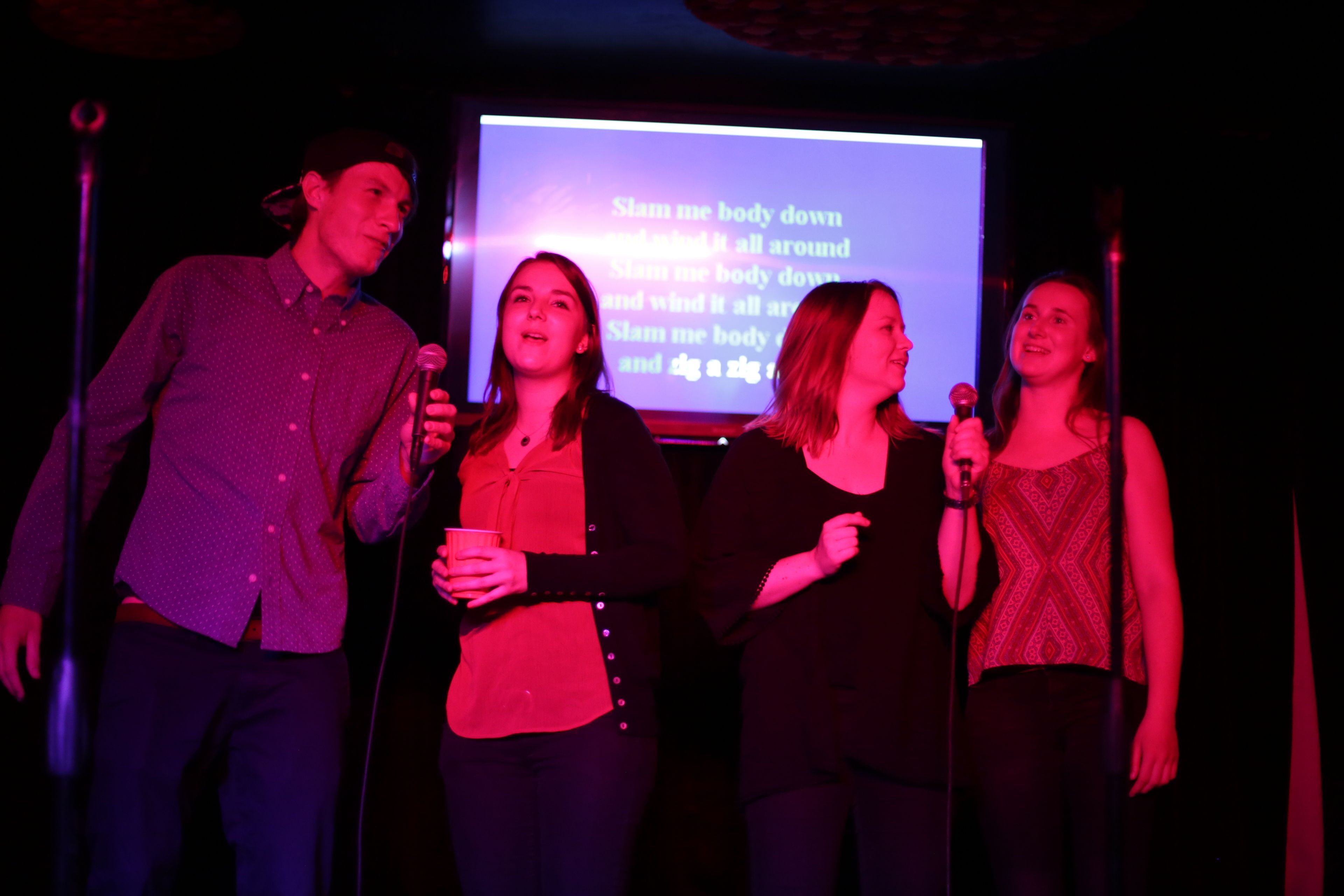 A group of people on a stage with a screen displaying text.