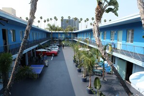 A courtyard with a pool table, potted plants, and a red car parked in the background. - Banana Bungalow Hollywood Hotel & Hostel (Los Angeles)