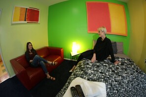 A room with a red couch, a bed with a black and white polka dot bedspread, and a lamp on a side table. - Banana Bungalow Hollywood Hotel & Hostel (Los Angeles)