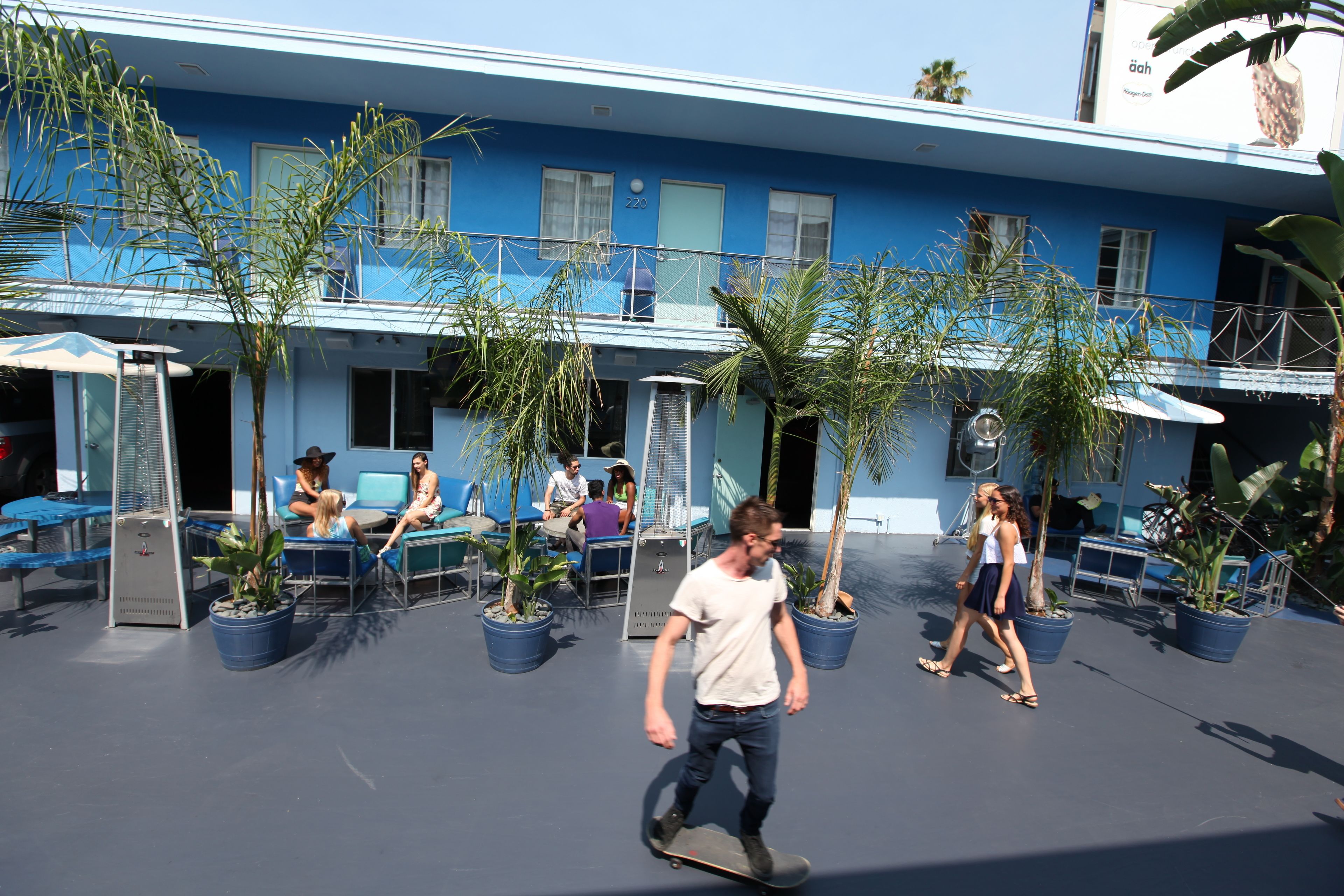 Un bâtiment bleu doté d’un balcon, de plantes en pot et d’un espace extérieur aménagé pour s’asseoir.