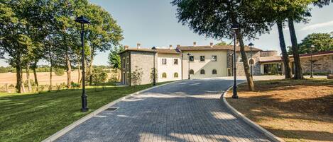 Un camino pavimentado que conduce a un edificio con fachada de piedra y ventanas arqueadas.