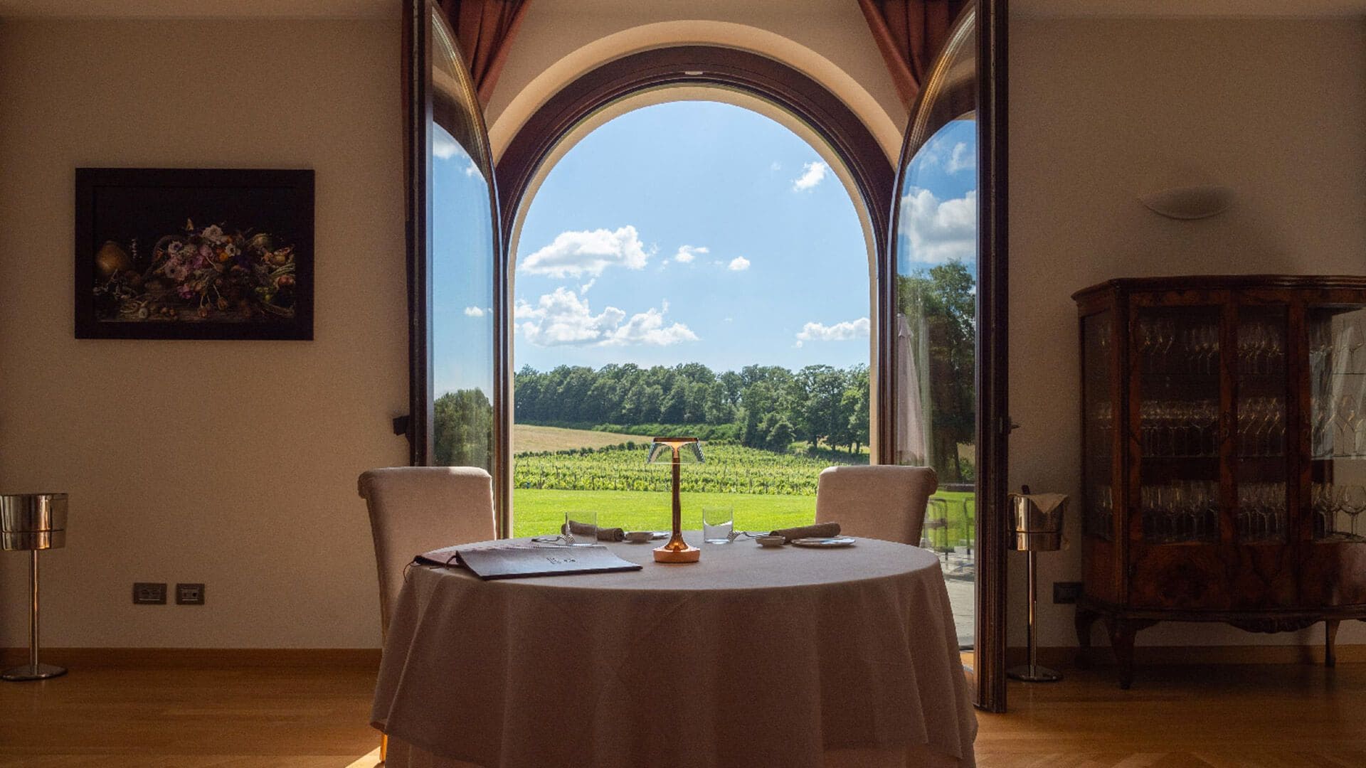 Mesa para dos lista, con vista a un viñedo a través de un arco.