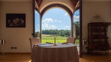 Mesa para dos lista, con vista a un viñedo a través de un arco.