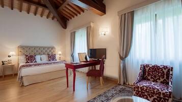 A hotel room with a bed, a desk, a chair, a television, and a sofa.