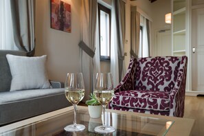 En moderne stue med en sofa, en mønstret lænestol og to glas hvidvin på et glasbord.