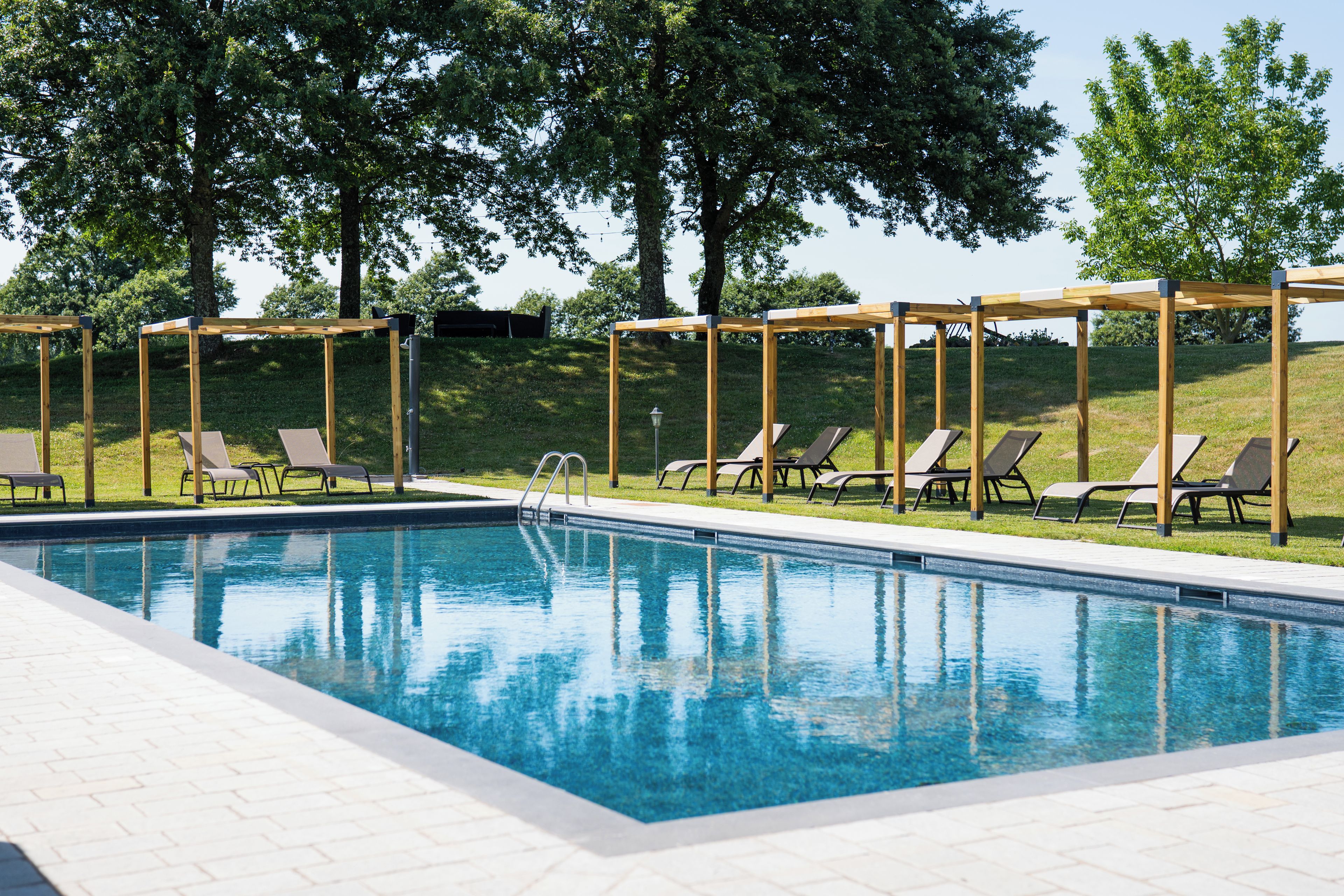 Una piscina con sillas de descanso y una pérgola.