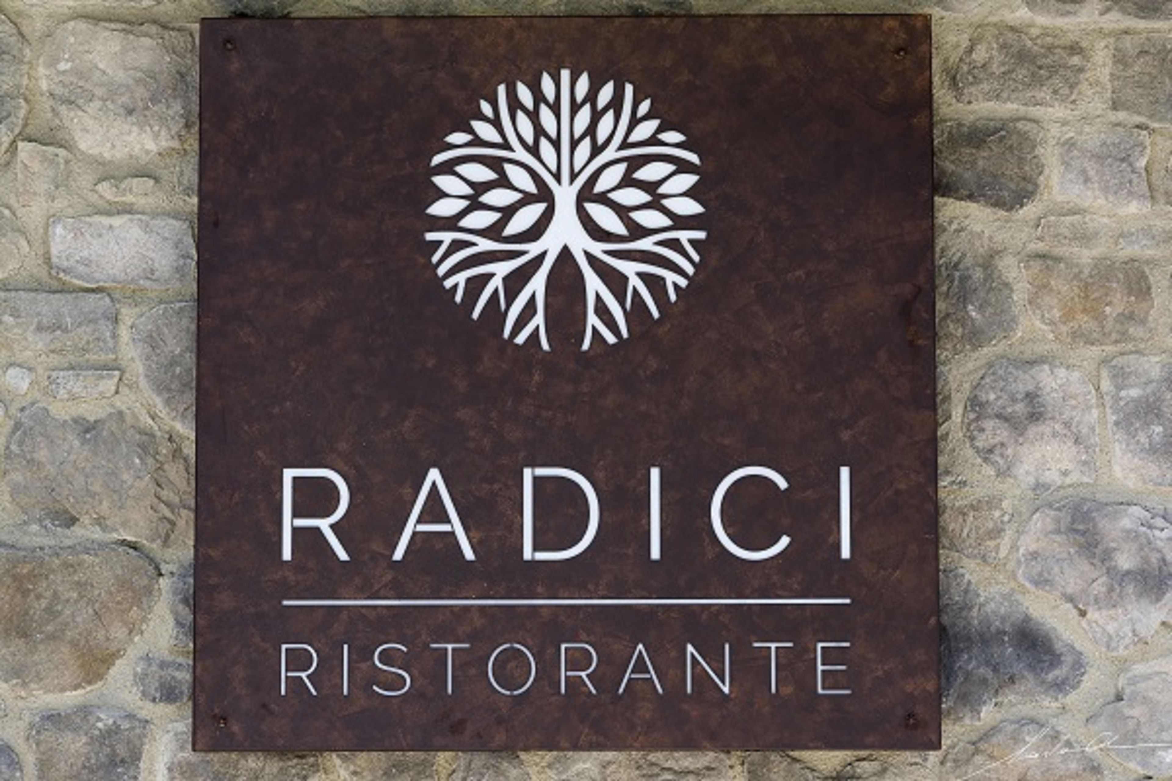 Segnaletica per il ristorante Radici, con logo raffigurante un albero.