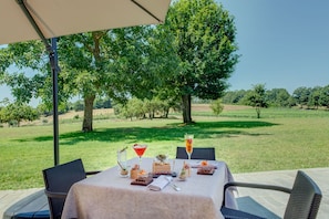 An outdoor dining area with a table set for two, surrounded by chairs, under a canopy. - Borgo La Chiaracia Resort & SPA (Castel Giorgio)