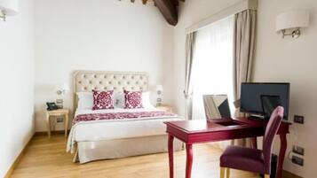 A bedroom with a bed, bedside table, lamp, TV, and a chair.