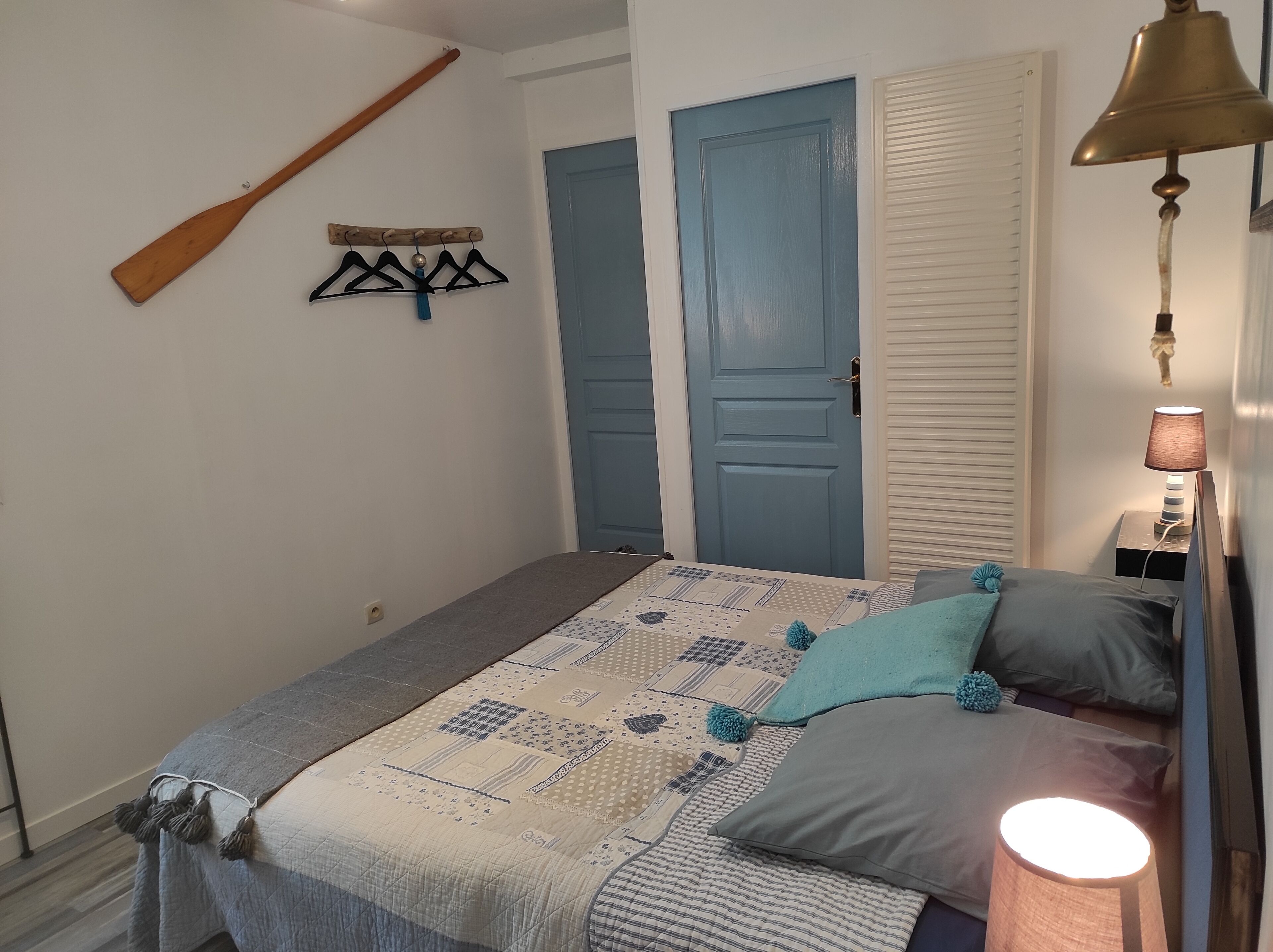 Une chambre à coucher avec un lit, une batte en bois, un porte-manteau fixé au mur et une table de chevet avec une lampe.