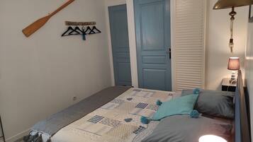 Une chambre à coucher avec un lit, une batte en bois, un porte-manteau fixé au mur et une table de chevet avec une lampe.