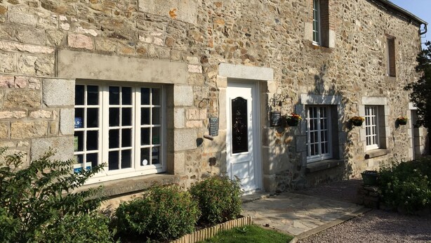 A stone building with large windows and a door, surrounded by a well-maintained garden. - Au Clos du Lit - Chambres d'hôtes (Lamballe-Armor)