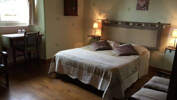 Un dormitorio con cama, mesitas de noche, un escritorio y una silla.