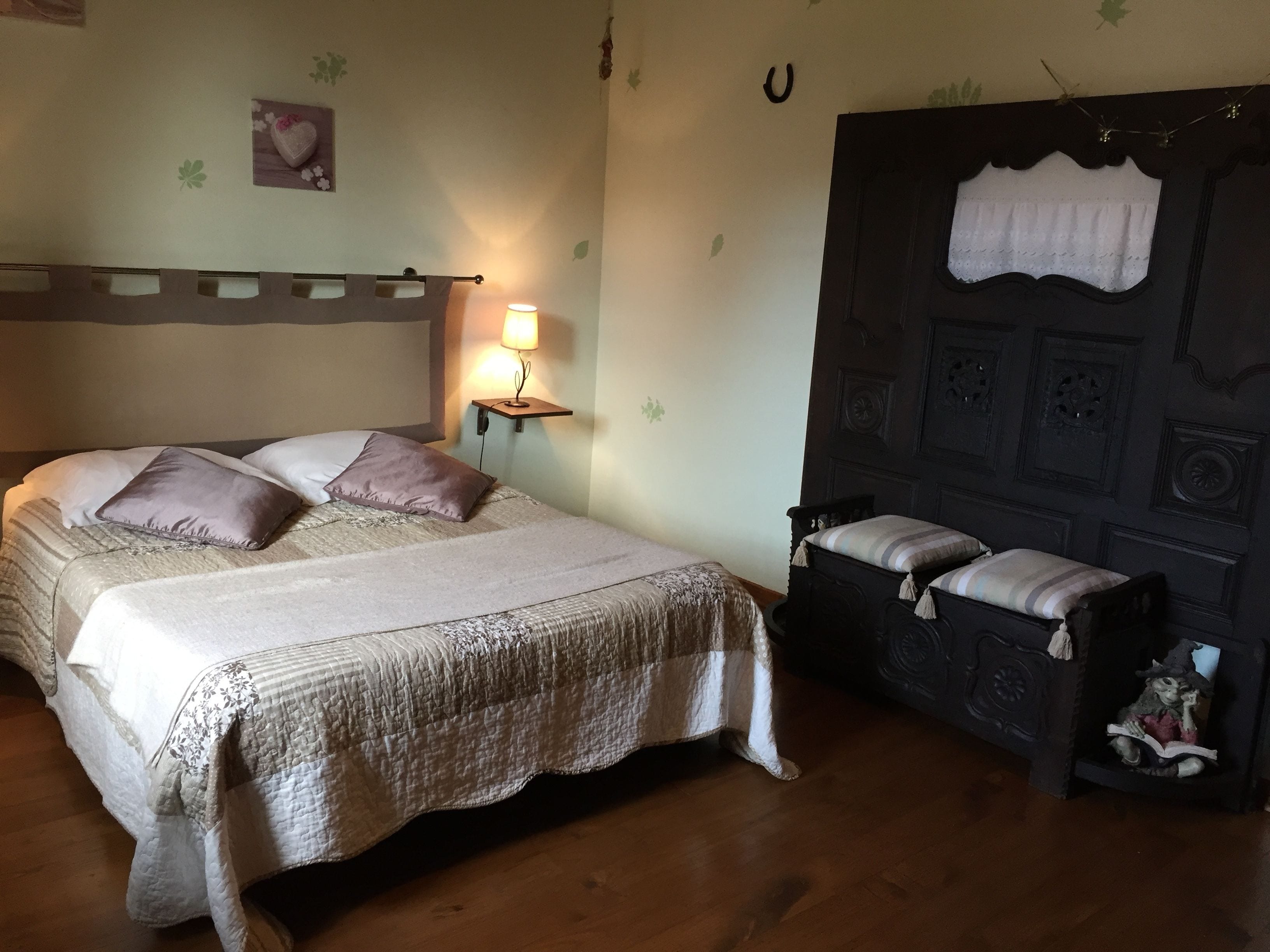Une chambre à coucher comprenant un lit, une table de chevet, une lampe et une petite étagère sur laquelle est posée une figurine.