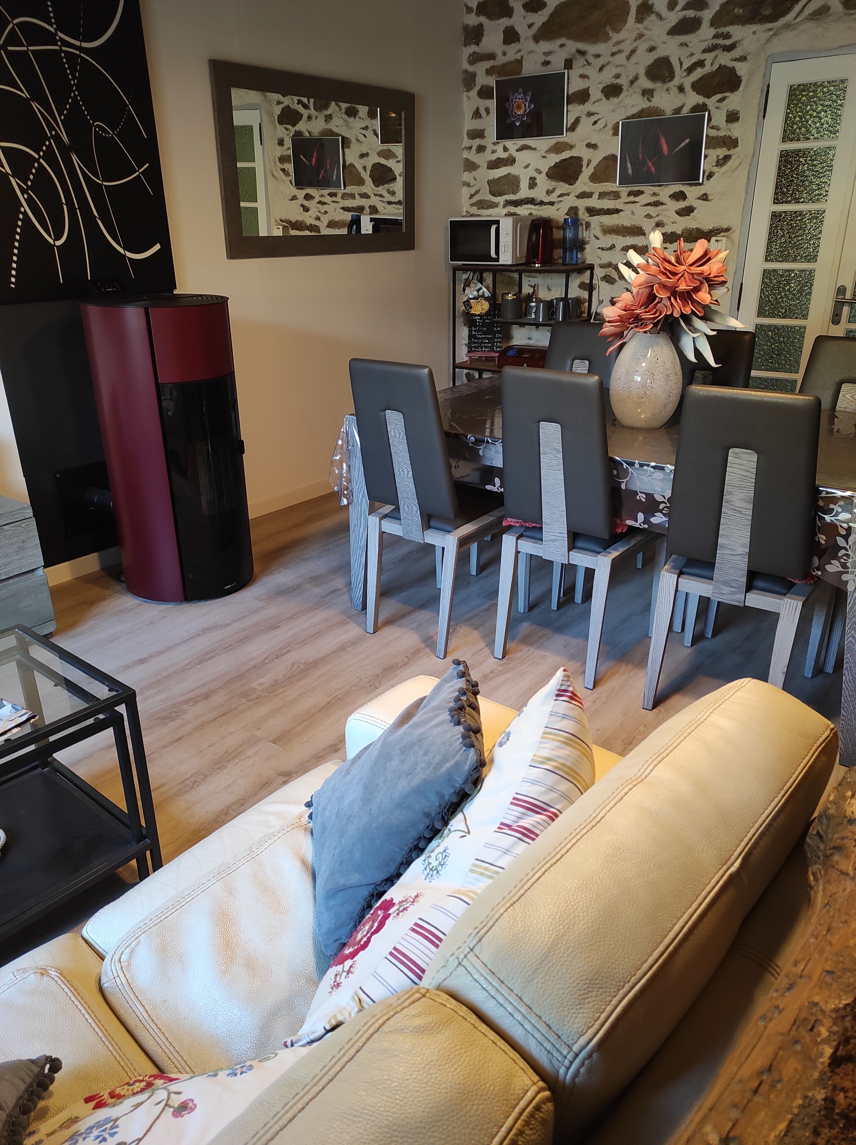 Ein Wohnzimmer mit einer Couch, Sesseln, einem Couchtisch, einem Kamin und einer Steinwand mit Kunstwerken.