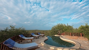 Un área de piscina con sillones de descanso y una terraza de madera.