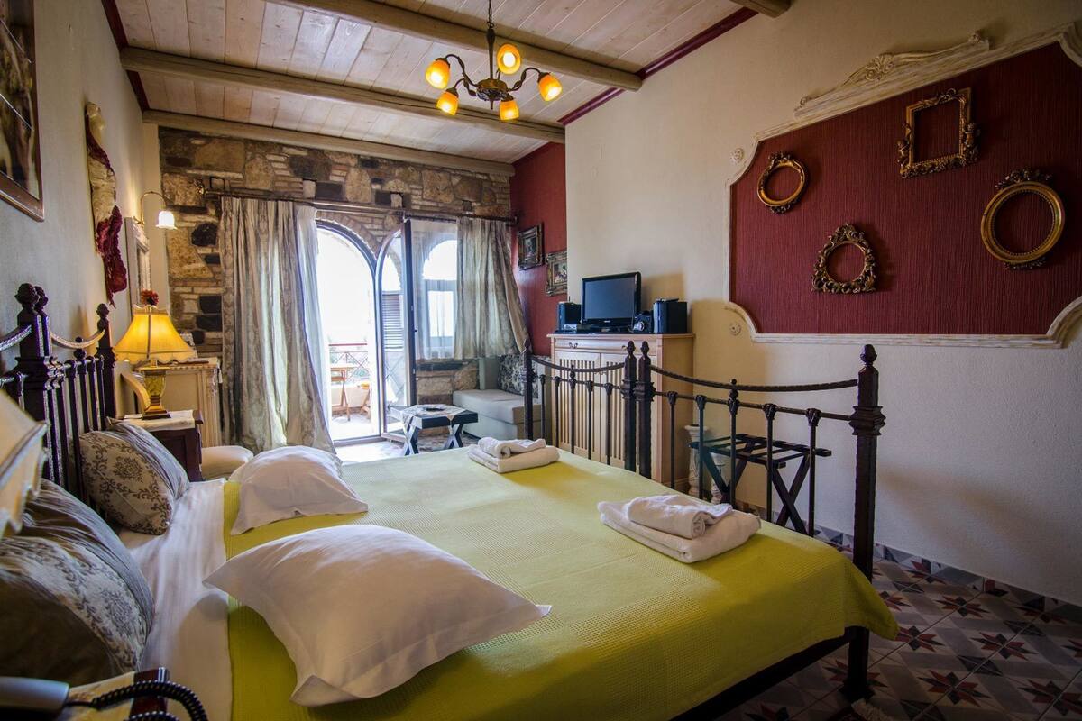 Una habitación con cama, televisión y pared de piedra.