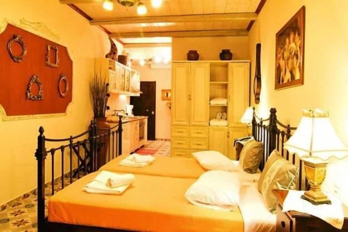 Una habitación de hotel con cama, mesita de noche, lámpara y armario.