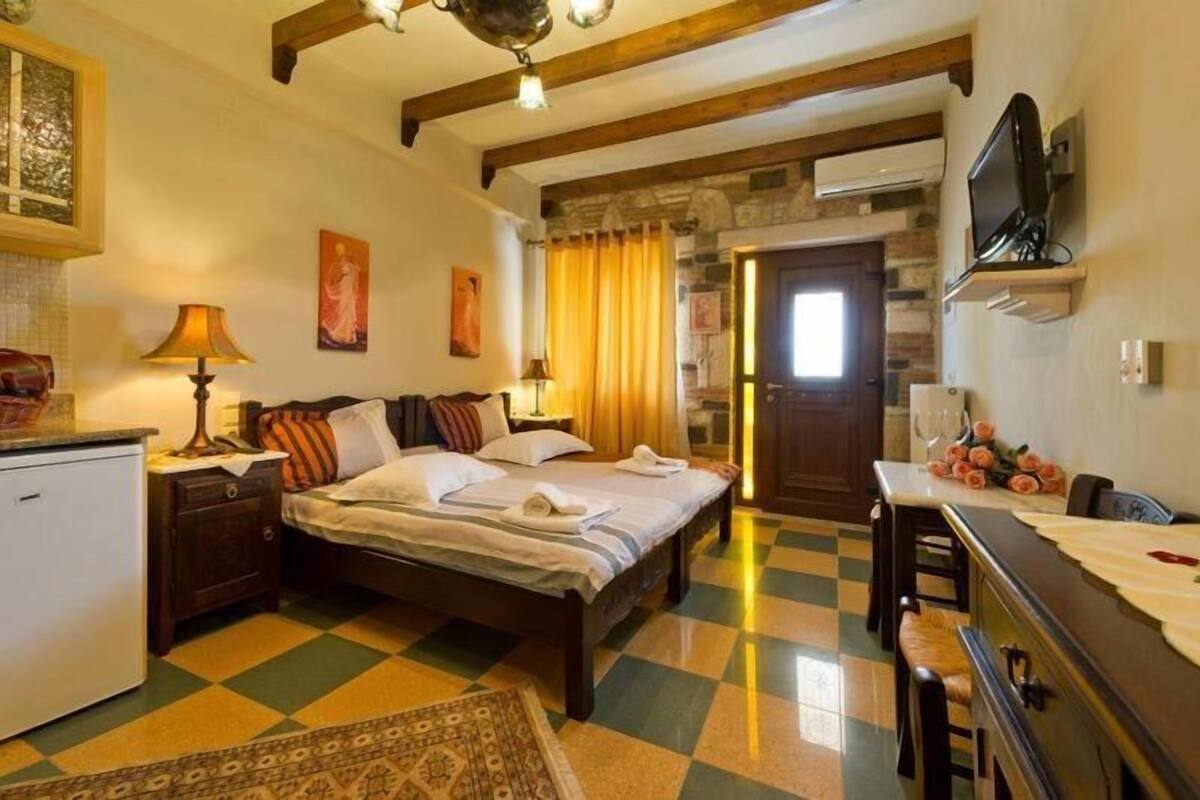 Una habitación de hotel con cama, mesita de noche, lámpara y piso de estampado de cuadros.